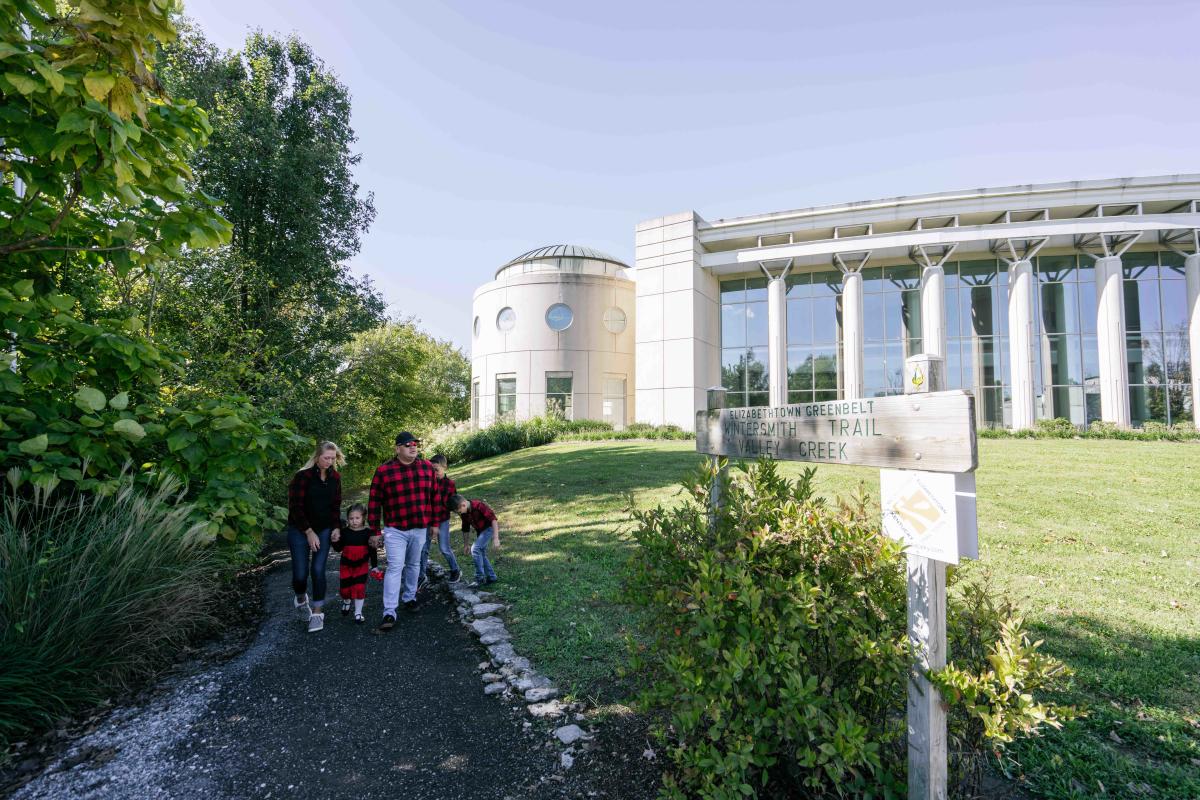 A family of four is walking along the Elizabethtown Greenbelt Wintersmith Trail
