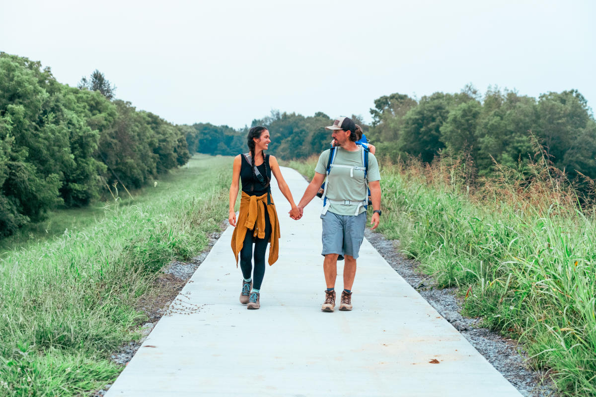 A couple is looking at one another, holding hands while walking a paved path at Buffalo Lake in Elizabethtown, Kentucky
