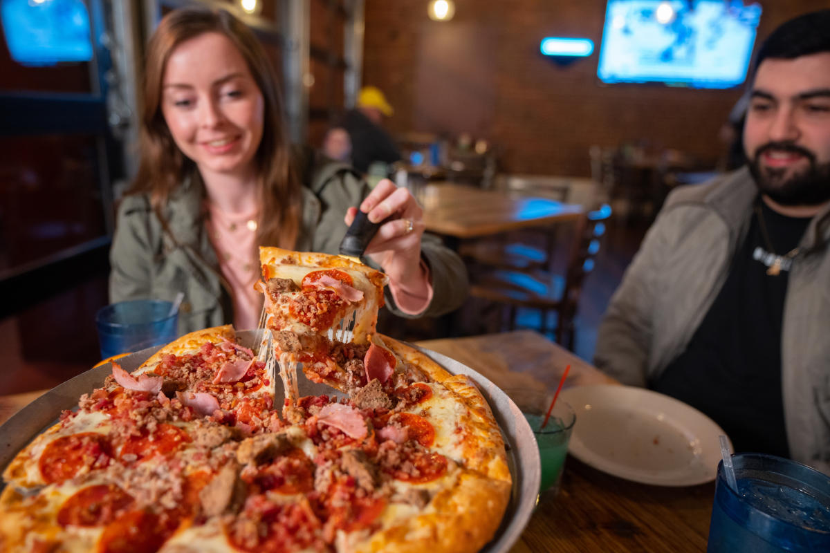 a couple enjoying slices of pizza at impellizzeris