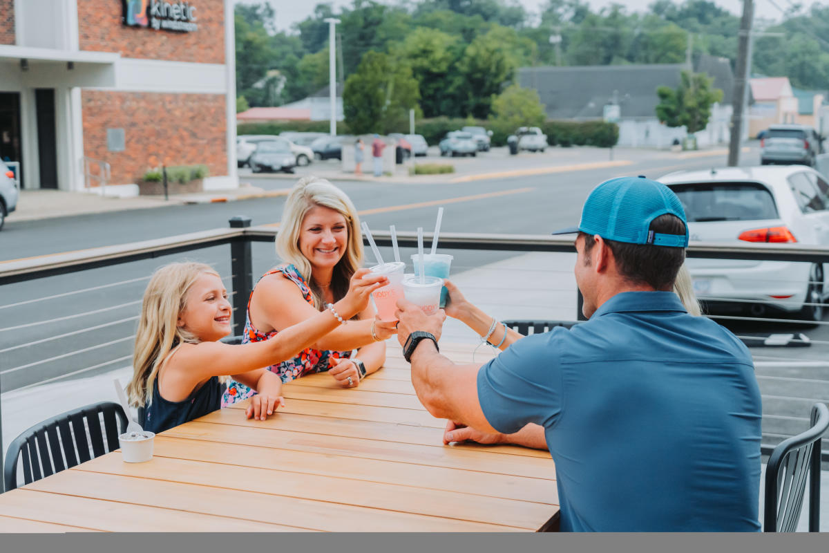 A family of four lifting their cups up to cheers, outside of Kuddy's in Downtown Elizabethtown