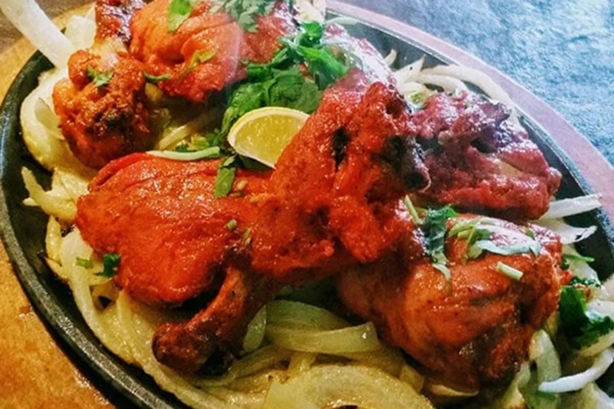 Sizzling platter of seasoned chicken with onions and a lime slice