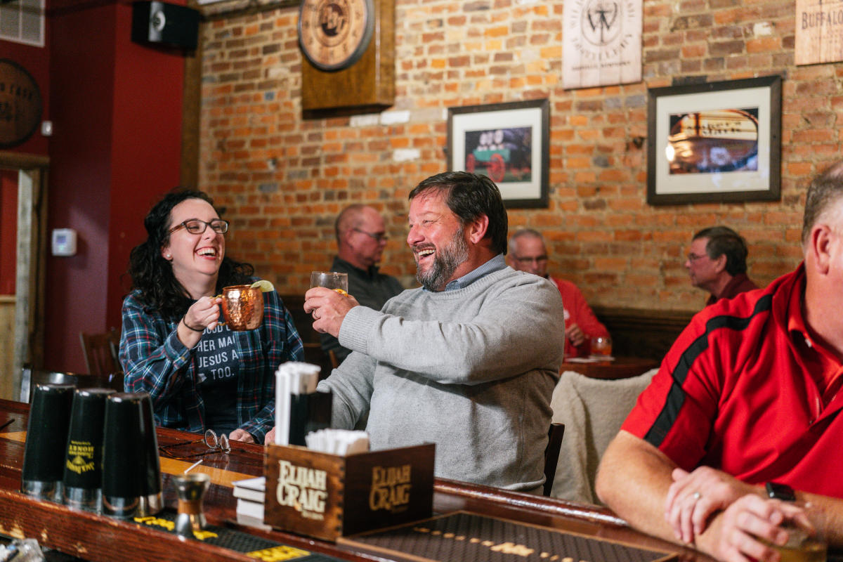 two people laughing over a drink at the bar of bbt