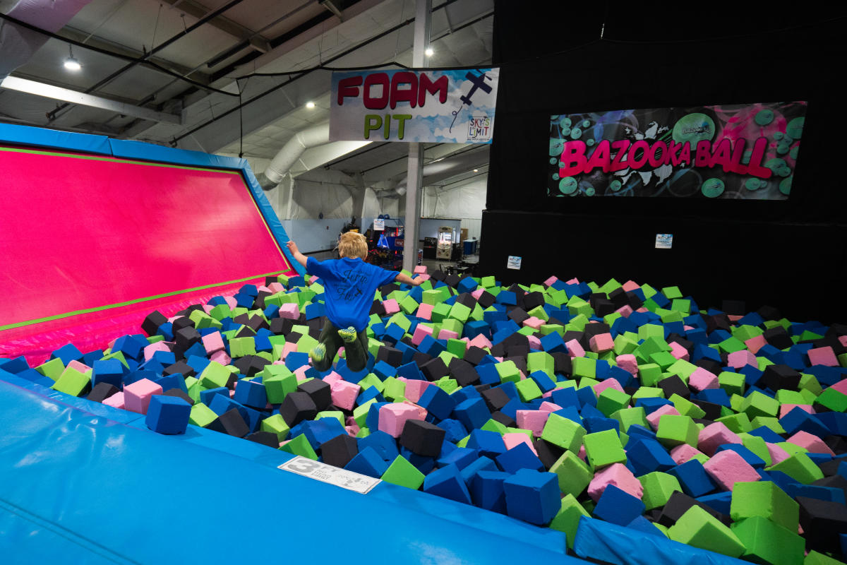 A boy jumping into a foam pit at Sky's the Limit Trampoline Park