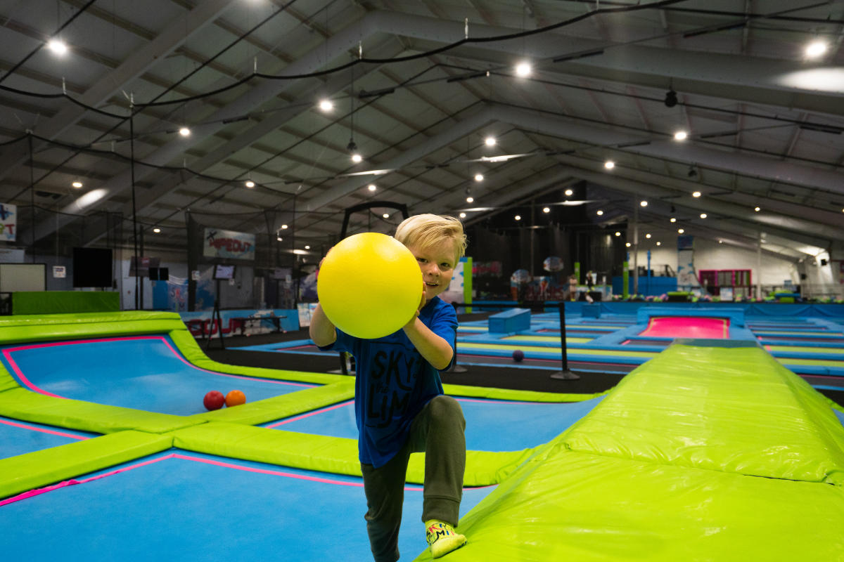 A boy about to throw a ball while jumping on the trampoline at Sky's the Limit
