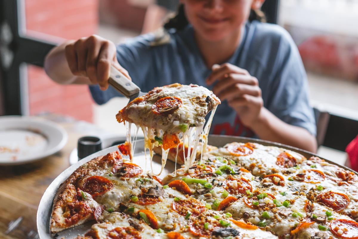 a little girl taking a slice from a pizza at impellizzeris
