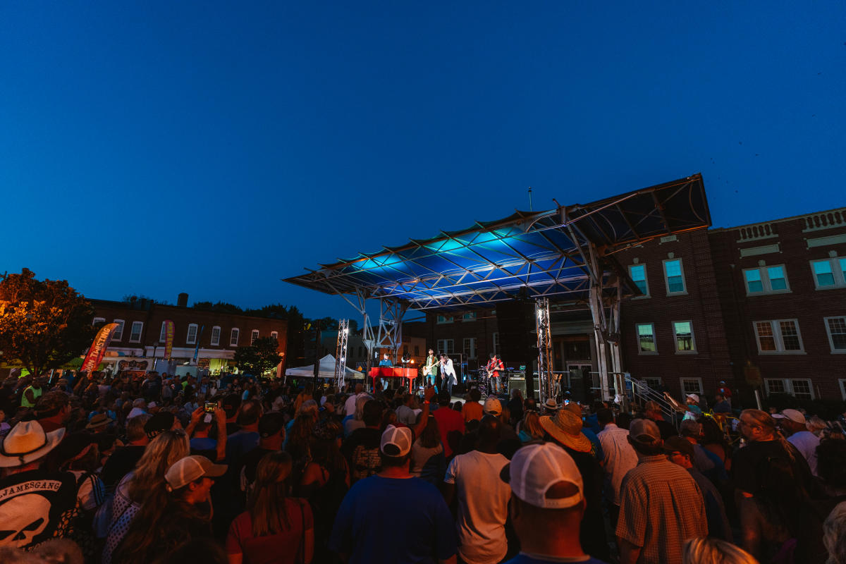 a crowd of people gathered around a stage in the center of downtown elizabethtown