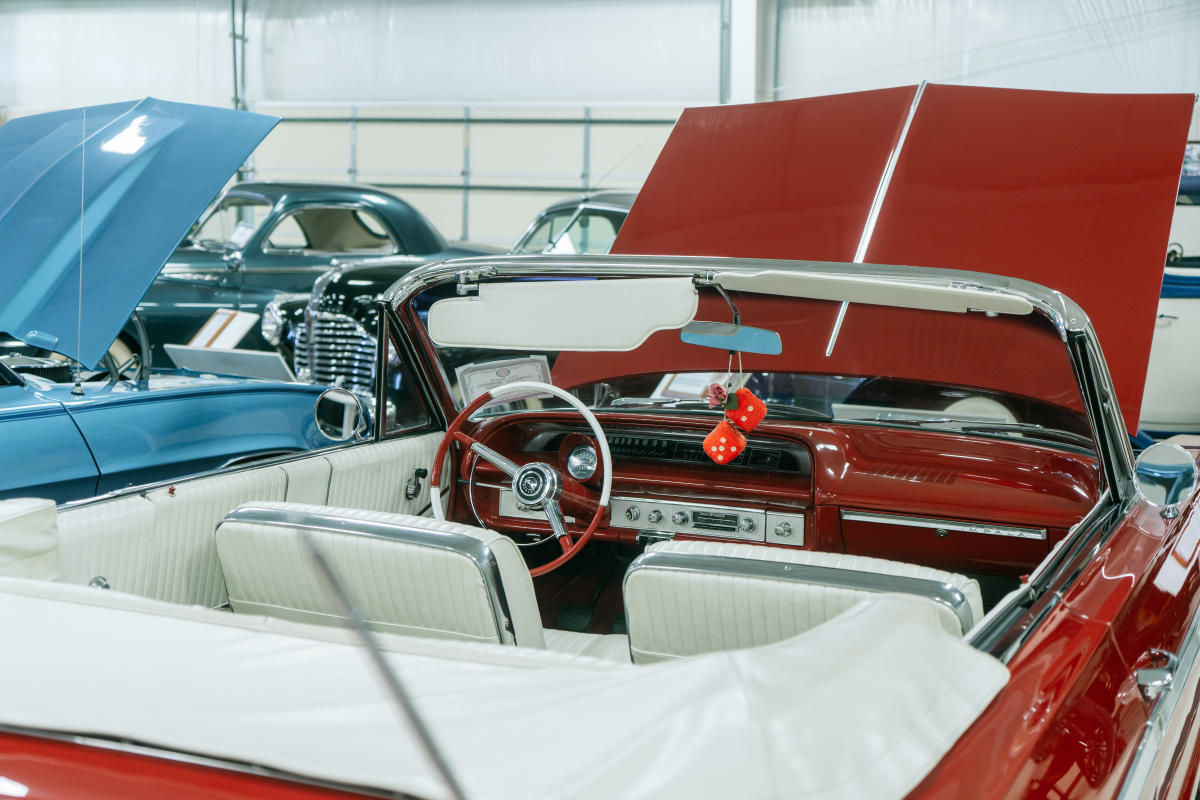 the white interior of a red classic car with the car hood open