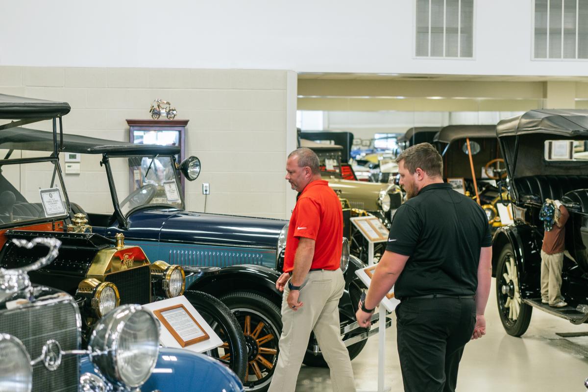 men observing cars at swope cars of yesteryear museum