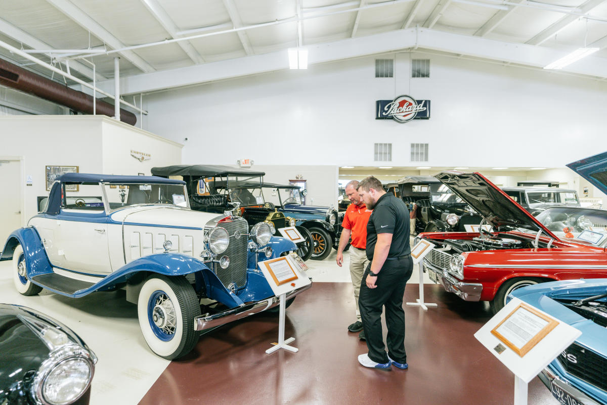 two mean reading a placard in a room of classic cars at swope cars of yesteryear musuem