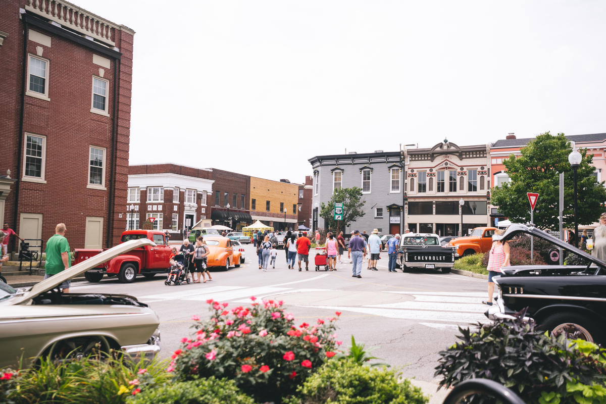 cars with hoods up line the streets as people observe cruisin the heartland