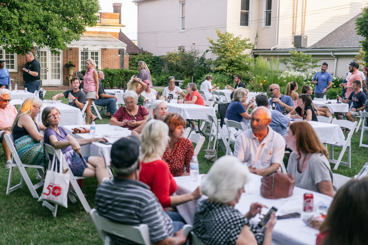 crowd sitting and gathered at tables at tavern in the garden