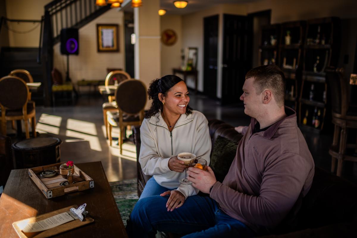 Two people smiling and having a drink at Revival Vintage Spirits bar in Downtown Elizabethtown, KY.