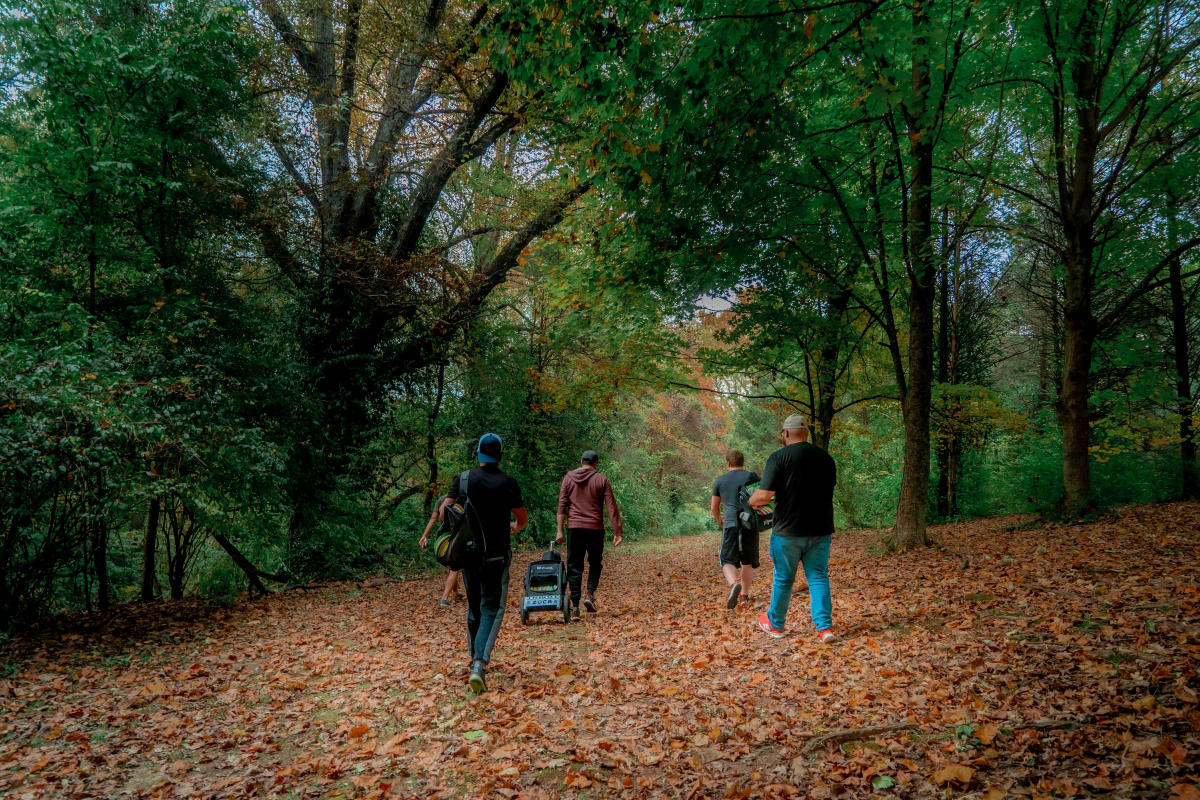 disc golf players walk to the next hole through a wooded path