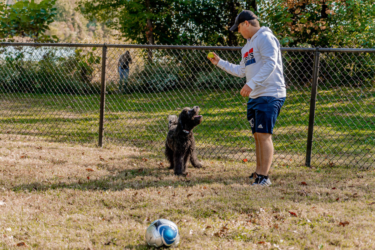 A boy playing with a black golden doodle at the Freeman Lake Dog Park