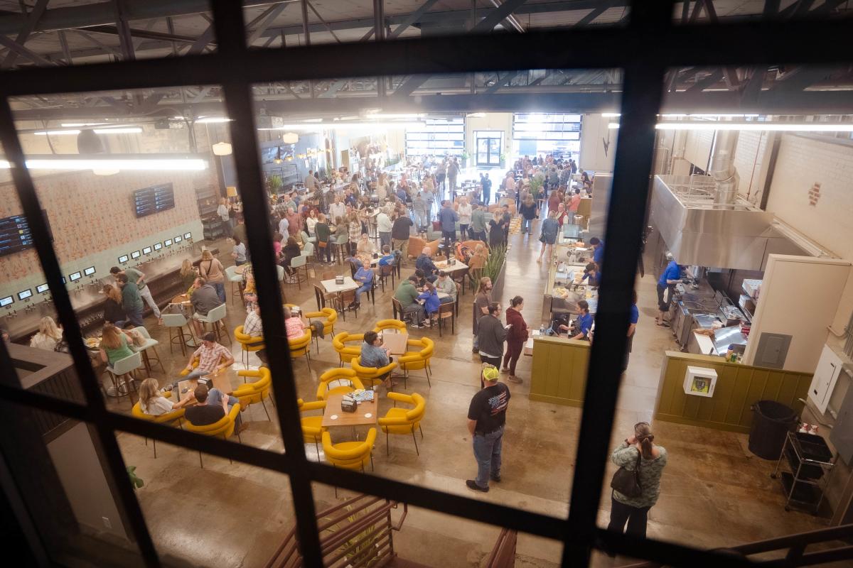 Through the window on the outside of Social on Main, people are seated and standing in the inside of Social on Main in Downtown Elizabethtown