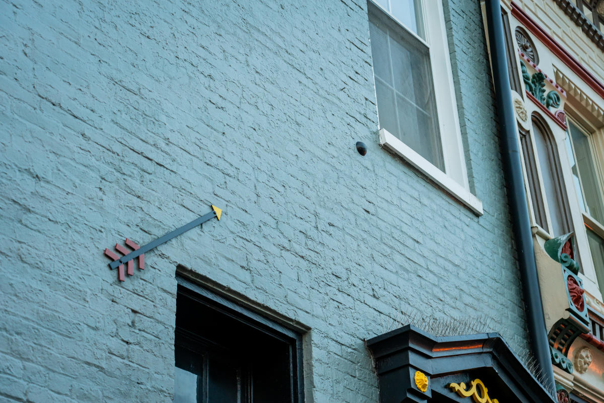 Close-up of a historic building's exterior with a decorative arrow embedded in the brick wall, highlighting architectural details in a downtown area