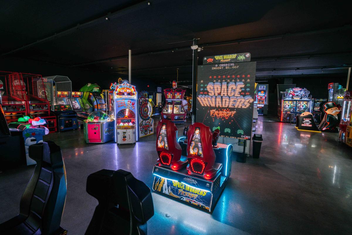 A darkened arcade filled with various illuminated gaming machines.