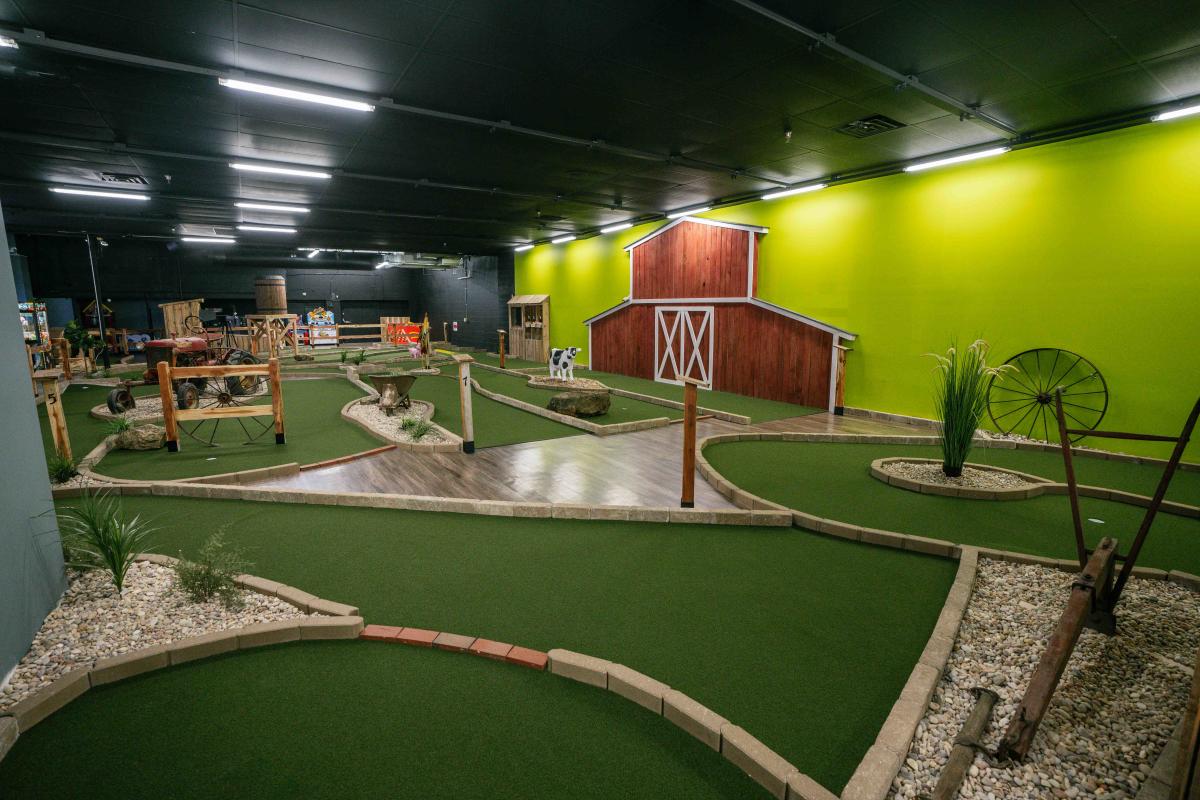 An indoor mini-golf course with a rustic barn-themed designs.