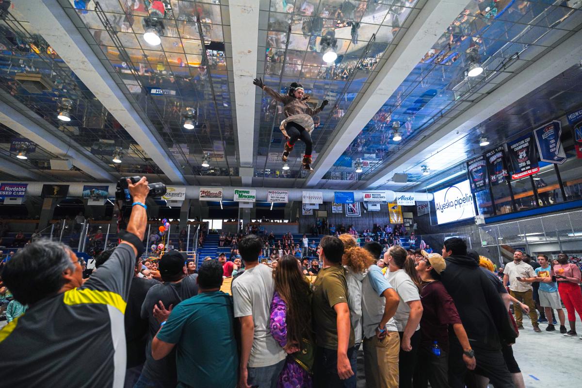 The blanket toss event at the World Eskimo-Indian Olympics. A group of people stand in a circle around a blanket while one person is tossed into the air at center of the circle.