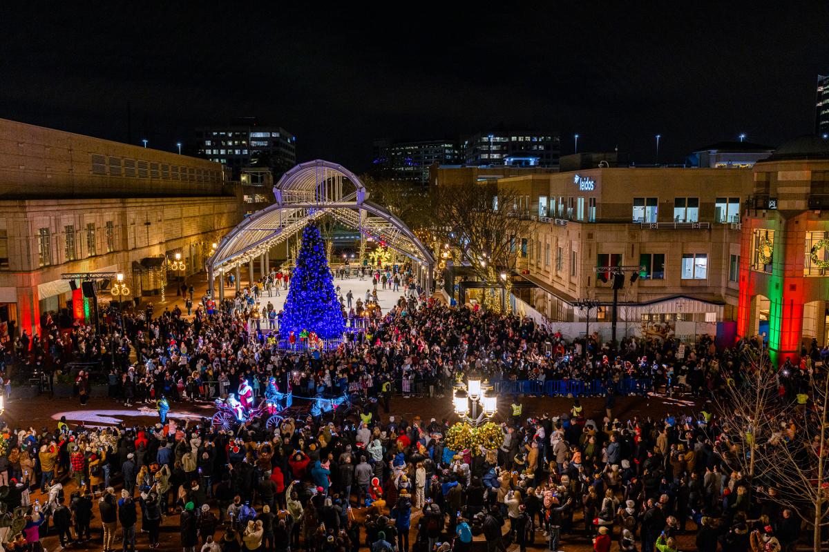A huge Christmas Tree in the middle with crowds of people and Santa walking down the parade.