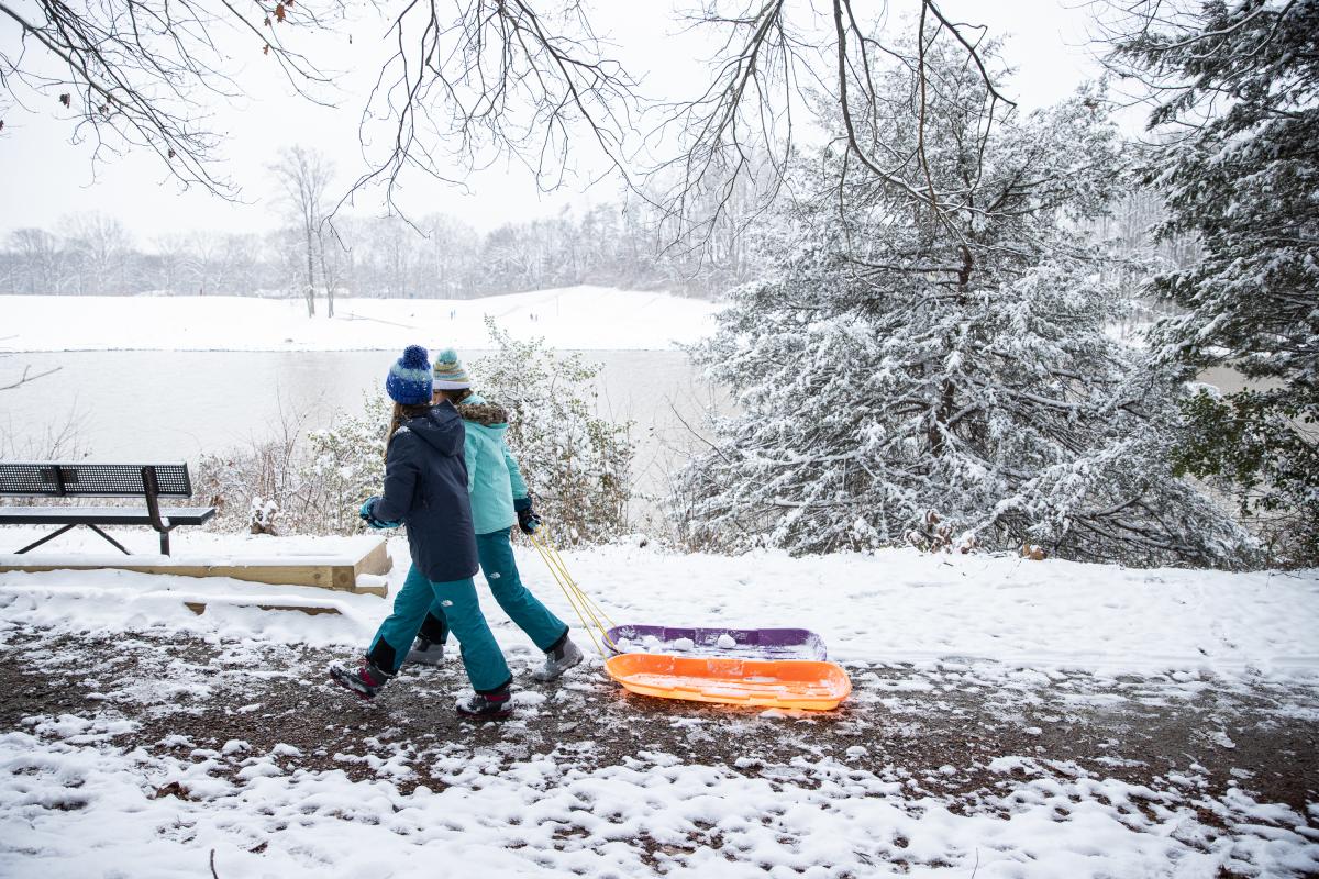 Two girls dragging their sled.