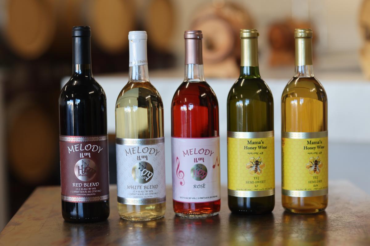 Five bottles of wine lined up next to each other on a table, all different varieties of wine