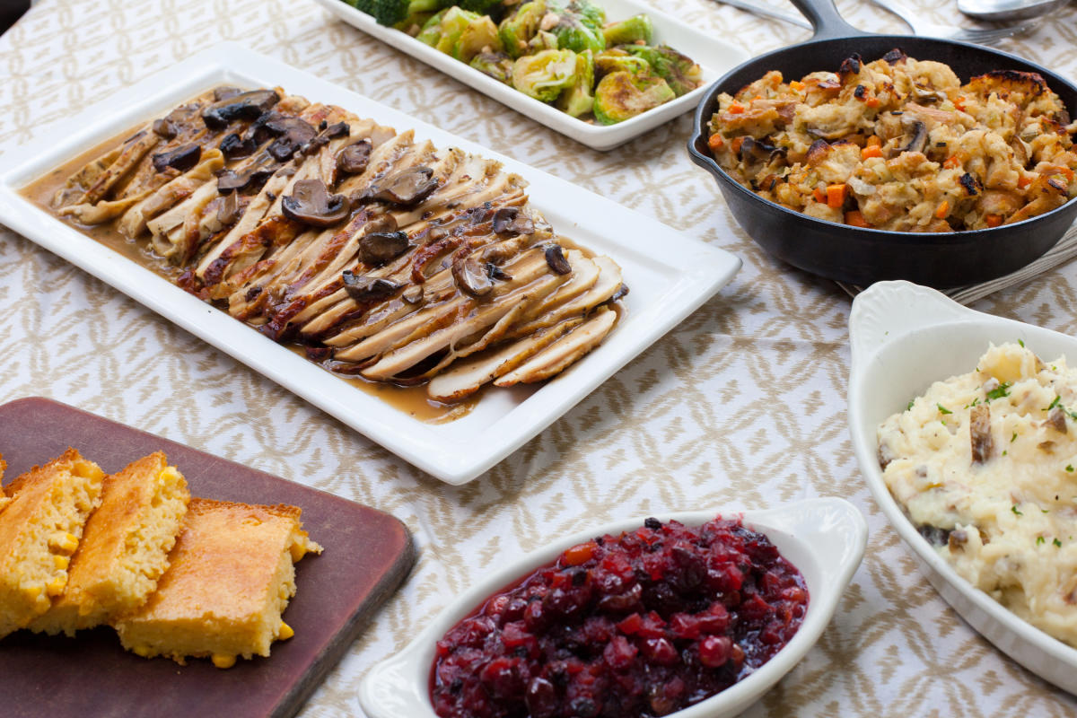 Six platters of traditional Thanksgiving entrees and sides, including cornbread, cranberries, potatoes, stuffing and turkey.