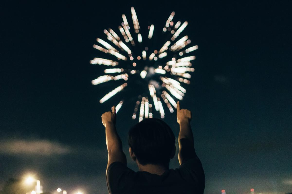 A Man Pointing Towards a Large Firework