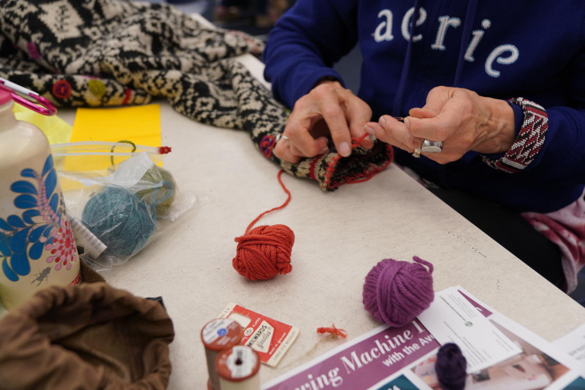 A woman repairing a piece of clothing with yarn.