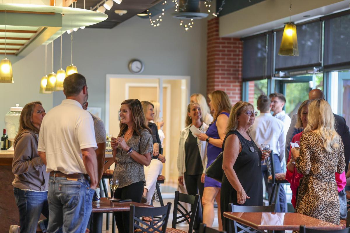 A group of people mingling at the bar area in the Drake Center.