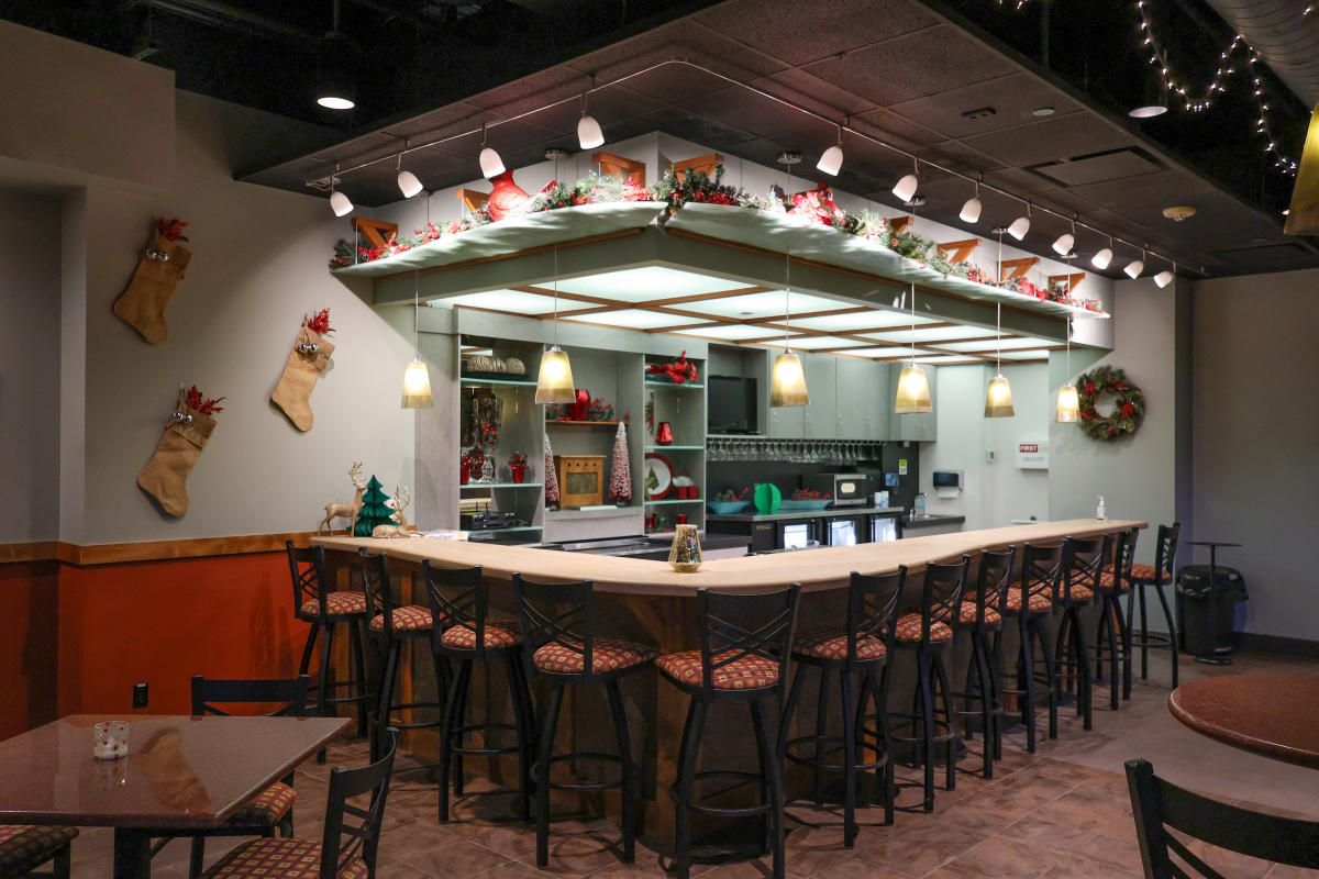 A cafe bar with stools at the bar and tables around the bar.