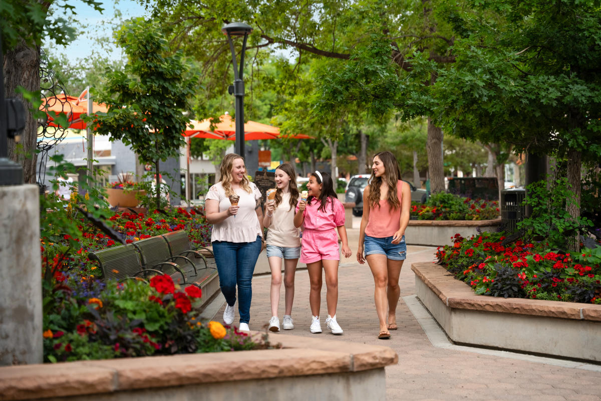 A family eats ice cream as they walk through Old Town Square in the summer