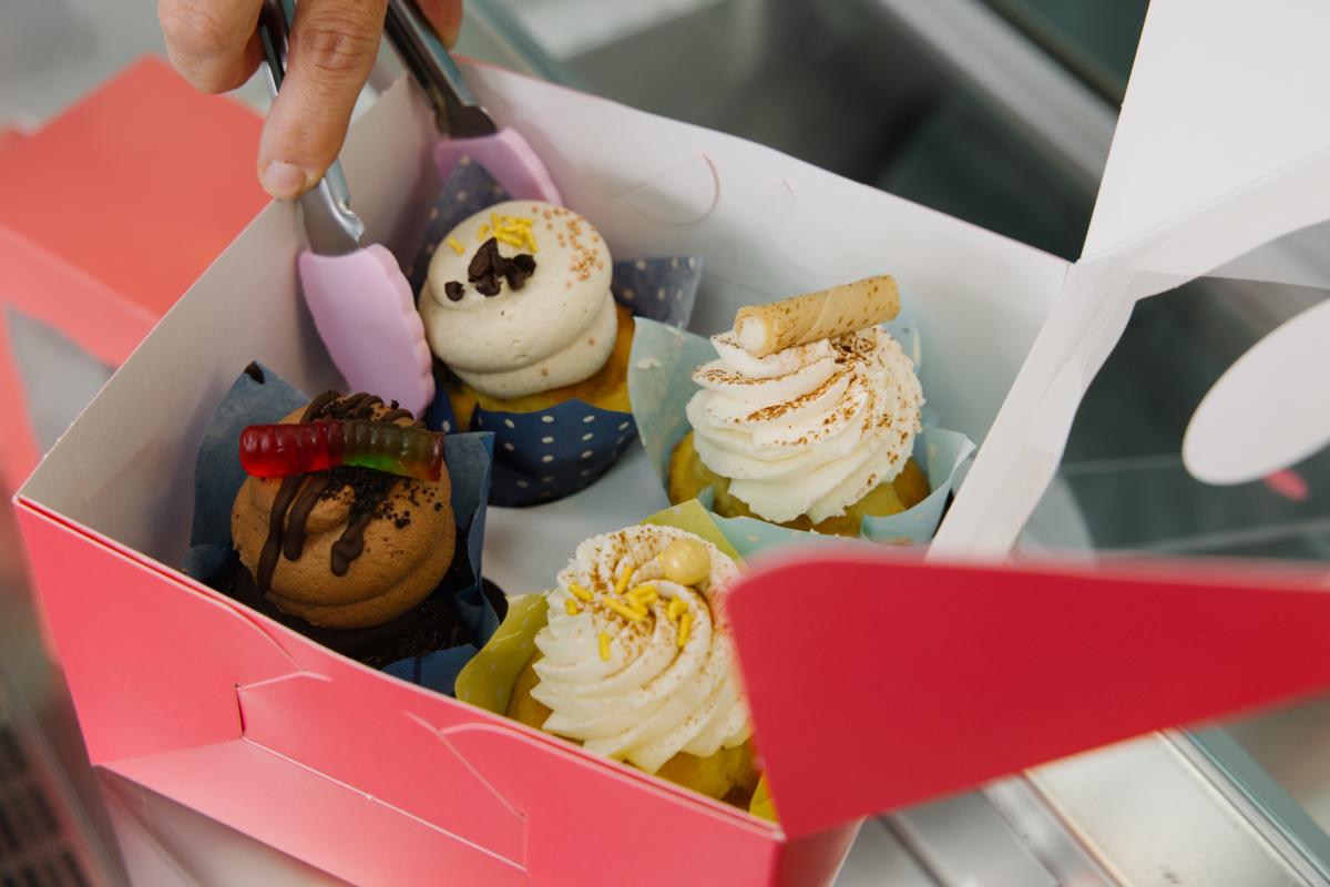 Four cupcakes being put into a box to take them to go