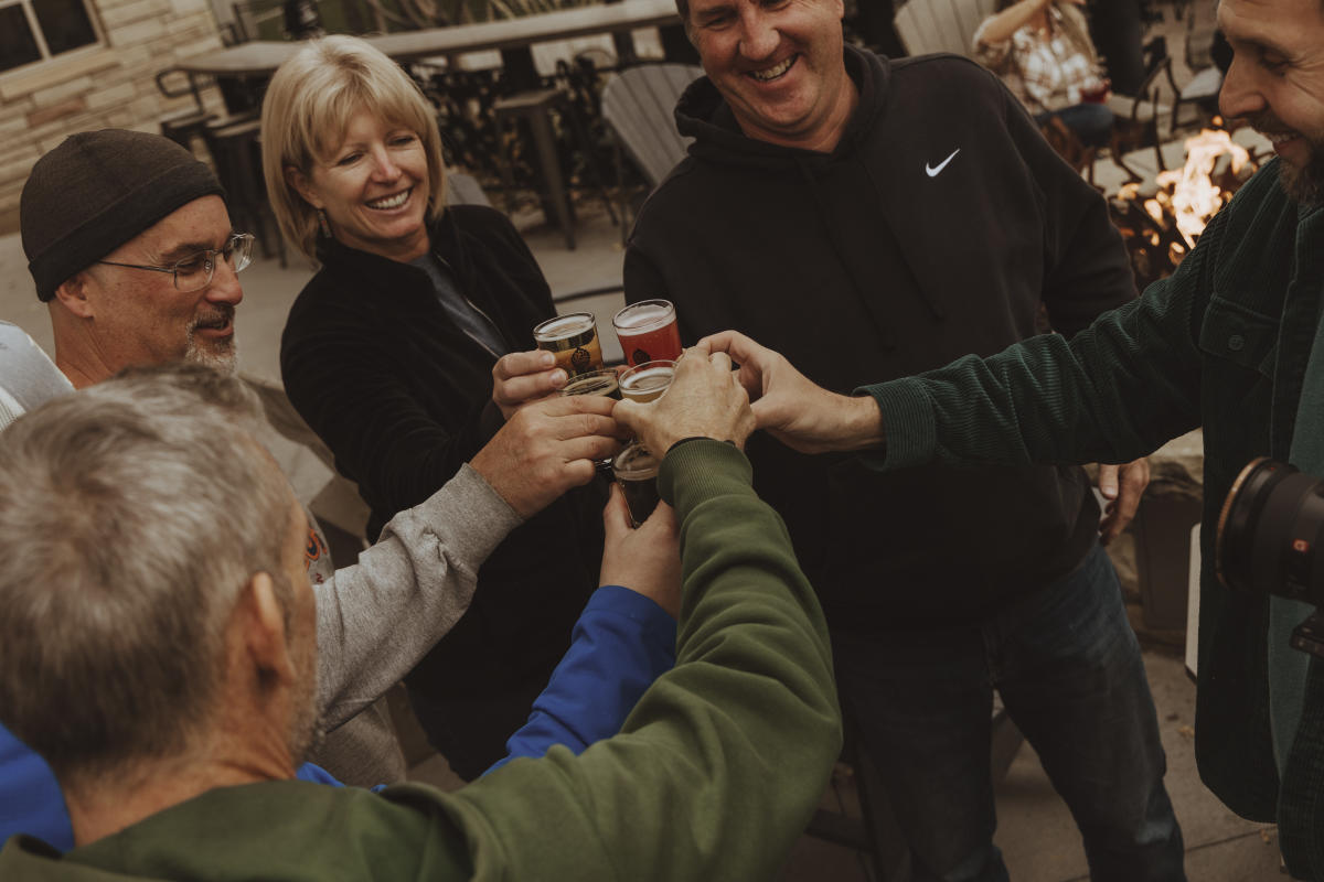 A group of people cheersing taster sizes of beer.