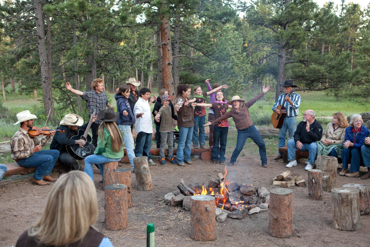 A group of people singing around a campfire