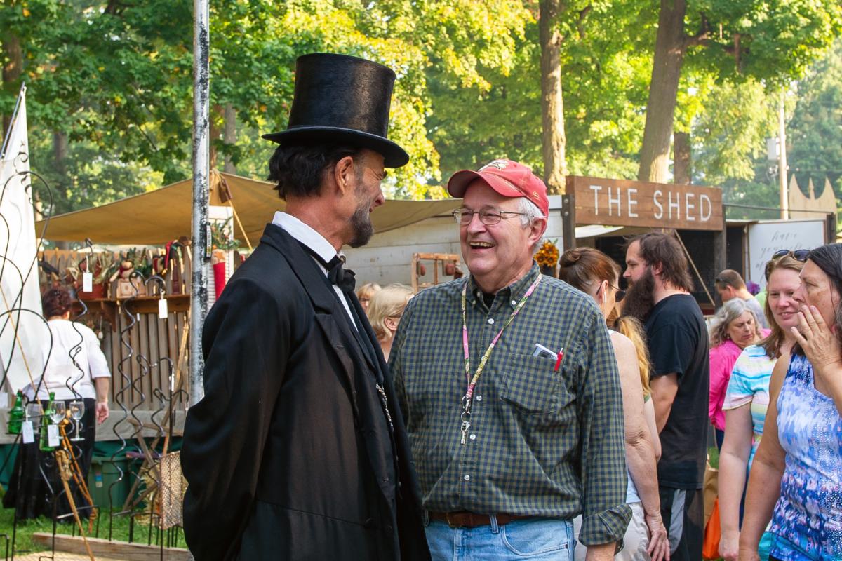 Abraham lincoln reenactor talks to an attendee at the johnny appleseed festival