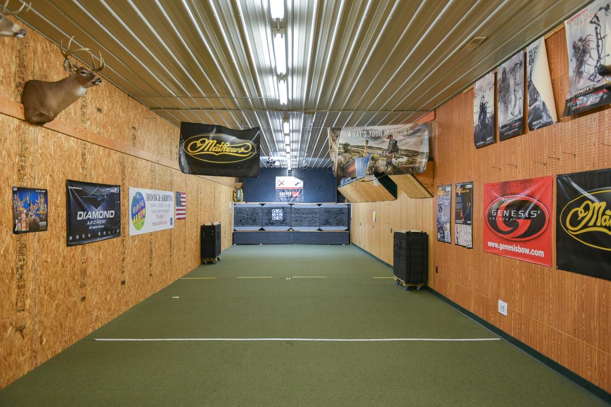 A Shooting range with banners along the walls, and targets at the very other side where the angle of the picture is pointing