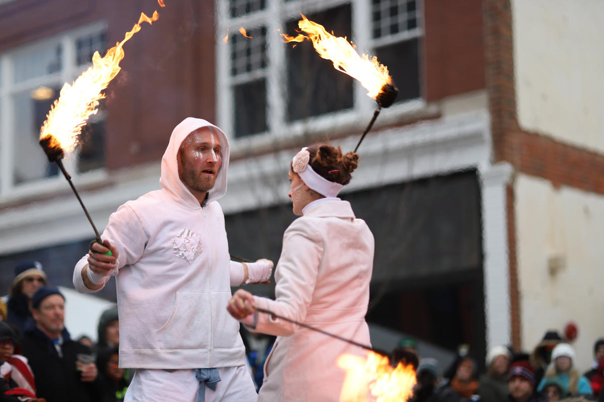 two fire dancers performing at a festival with spectators in the background