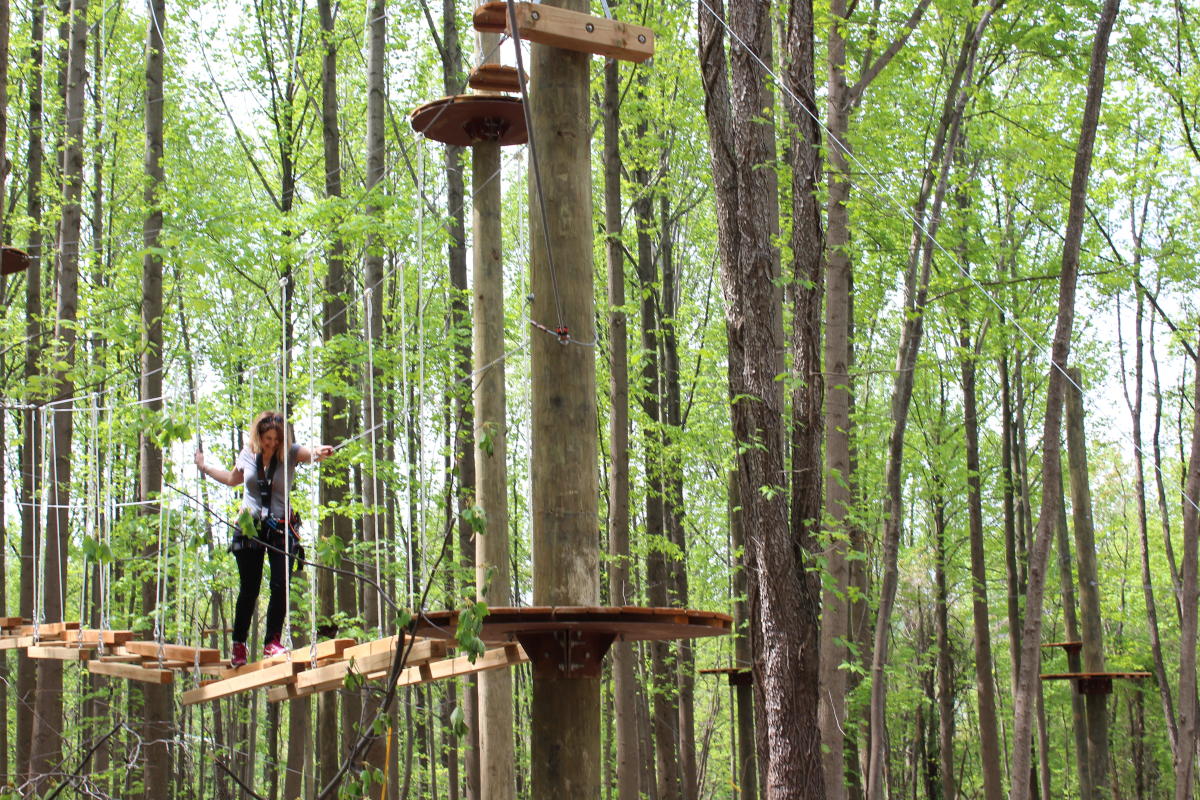 Woman crossing an elevated bridge at TreeTrekkers In Frederick County, MD