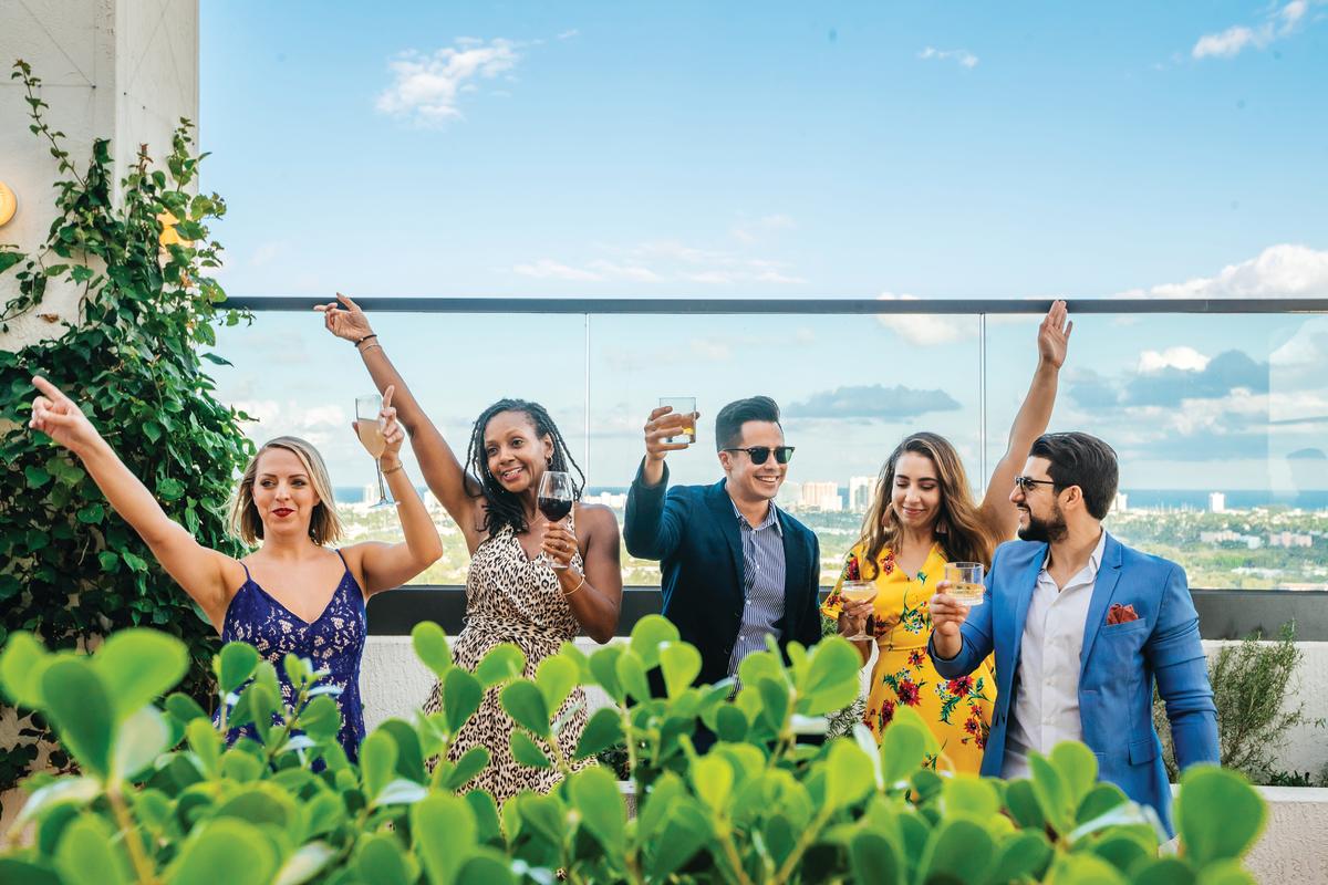 Friends raising glasses to toast from a rooftop bar in Fort Lauderdale