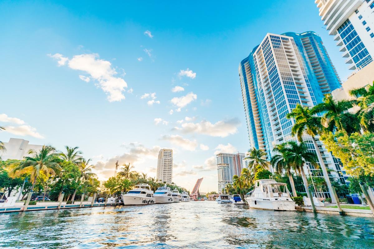 A view from the New River of yachts and high rises with a very blue sky and some puffy clouds