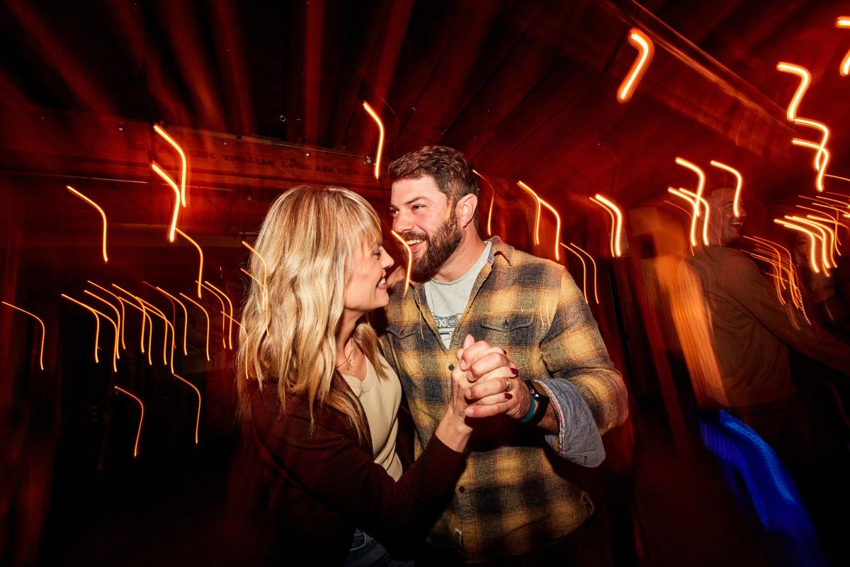 Two people dancing at night, with many lots around them.