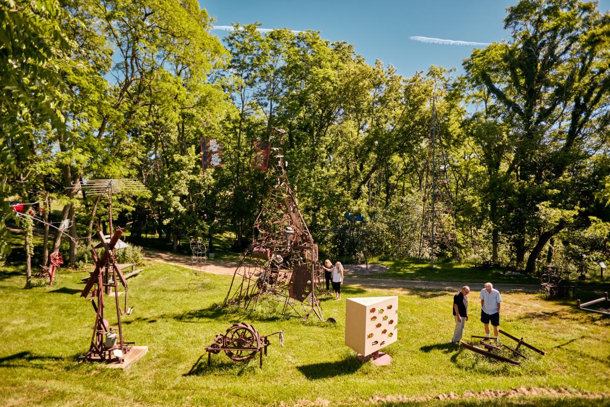 Sculpture park in the middle of the day, four people walking around and viewing the sculptures.