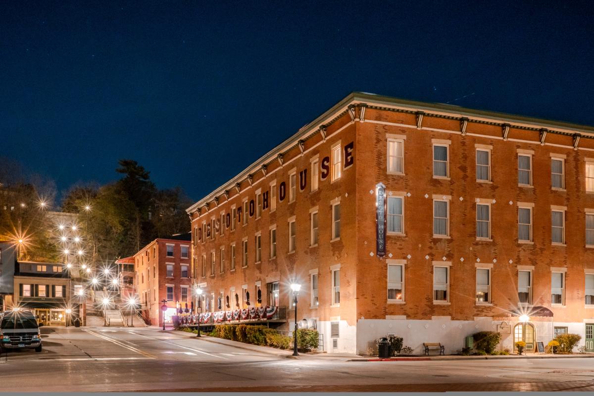Image of a brick building at night, with bright streetlights going up the hill nearby.