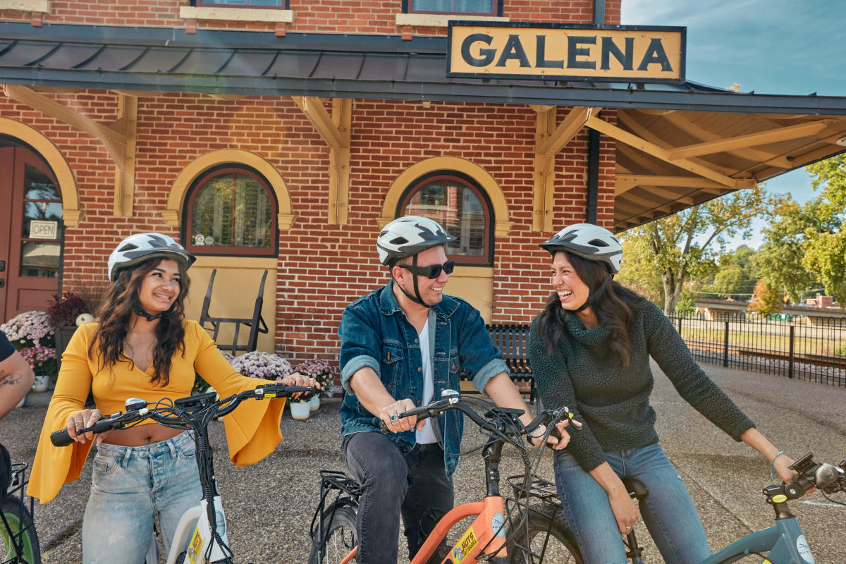 Four people on bikes in front of the Visitors Center in Galena, IL.