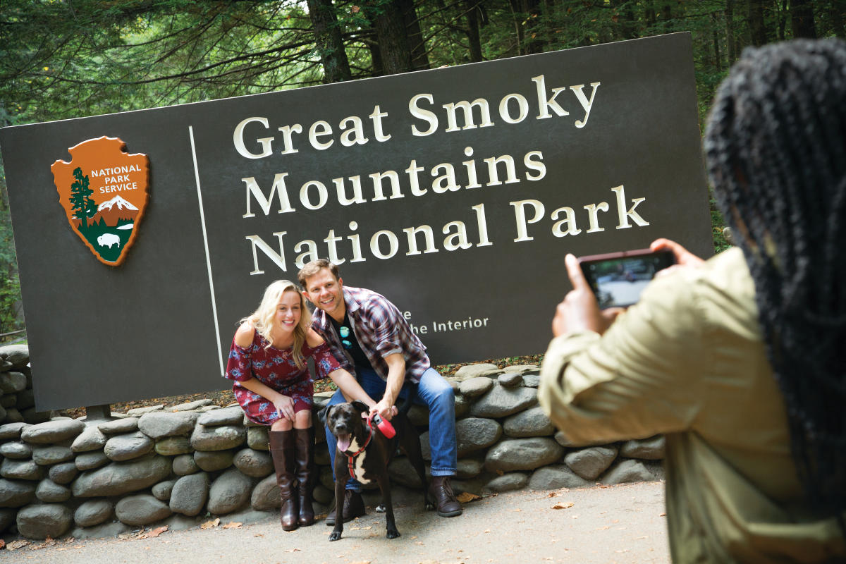 Couple and their dog posing in front of the Great Smoky mountains national park entrance sign