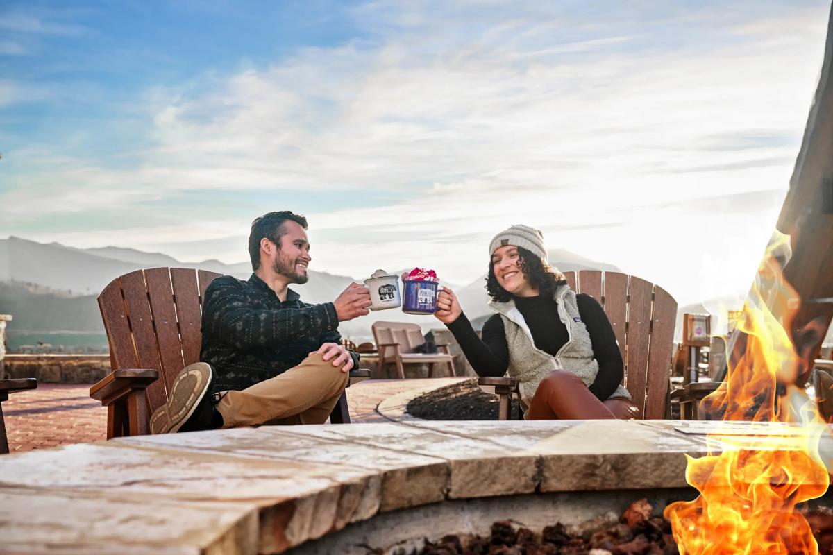 couple enjoy hot chocolate near fire pit