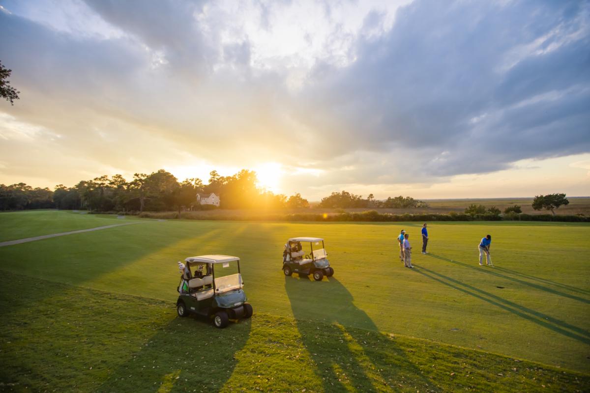 A group tees off under the light of a golden sunset at a golf course in Georgia's Golden Isles.