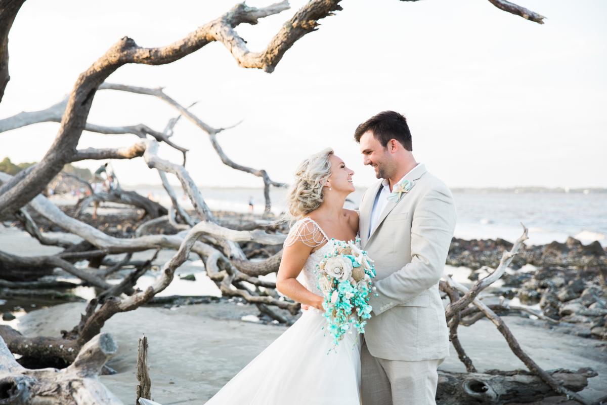 A couple posing on a Georgia beach for a photo after being married