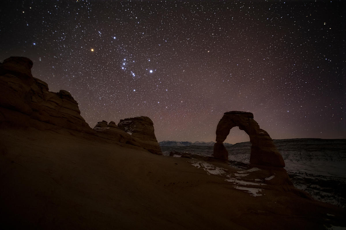 Delicate Arch silhouetted beneath a star-filled night sky in Arches National Park.